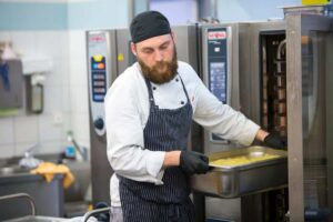 Rational SelfCookingCenter als großes Standgerät, aus dem ein Koch gerade einen GN-Behälter entnimmt